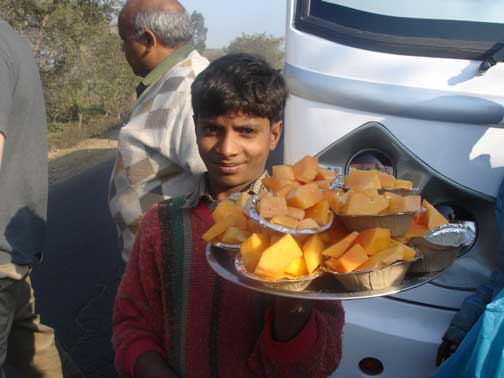 Boy selling cut fruit to cars waiting to cross the railroad tracks.