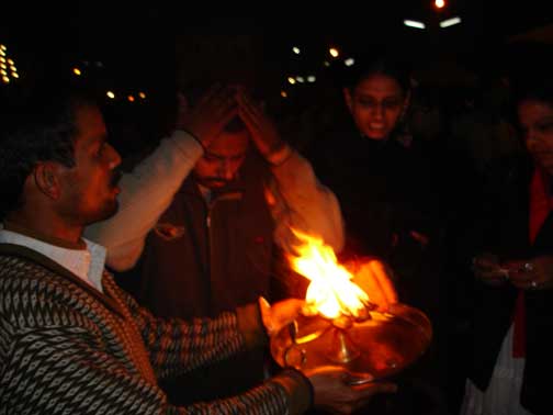 Man waving his hands over the fire.
