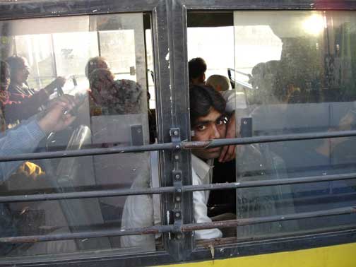 Man looking out the window of a public bus.