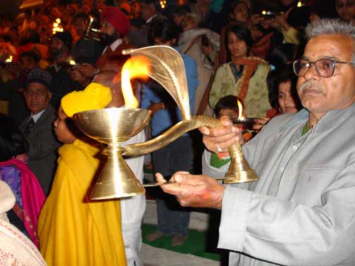 Worshipers pass the oil lamps.
