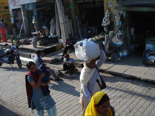 Women walking past open front stores in a small town.