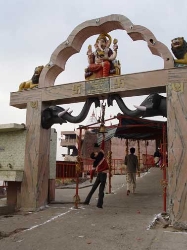 Worshiper rings bell before entering temple on mountain.